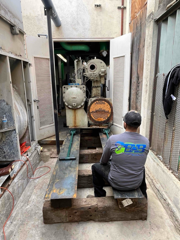 Technician working on large industrial machinery in a narrow mechanical room