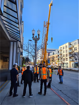 Construction workers in safety vests stand near crane on urban street