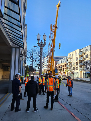 Construction workers in safety vests stand near crane on urban street