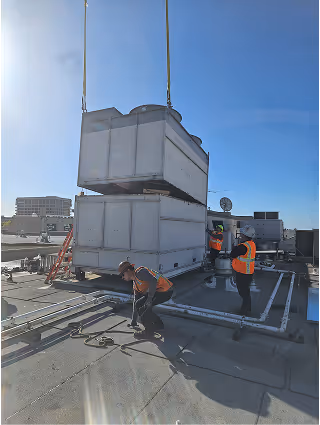 Workers installing large HVAC unit on commercial building rooftop