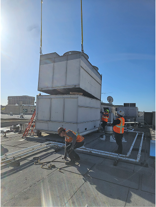 Workers installing large HVAC unit on commercial building rooftop