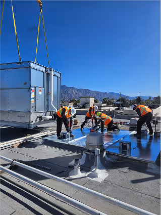 Construction workers installing roofing on commercial building with mountain backdrop