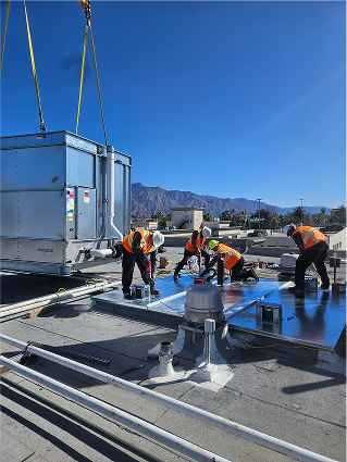 Construction workers installing roofing on commercial building with mountain backdrop