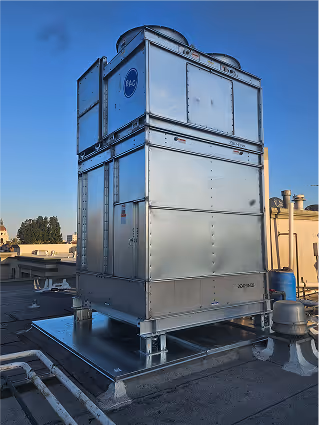 Large industrial cooling tower on a rooftop against blue sky