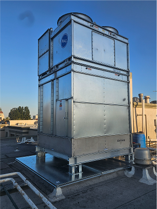 Large industrial cooling tower on a rooftop against blue sky