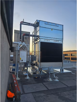 Large industrial cooling tower on rooftop at sunset
