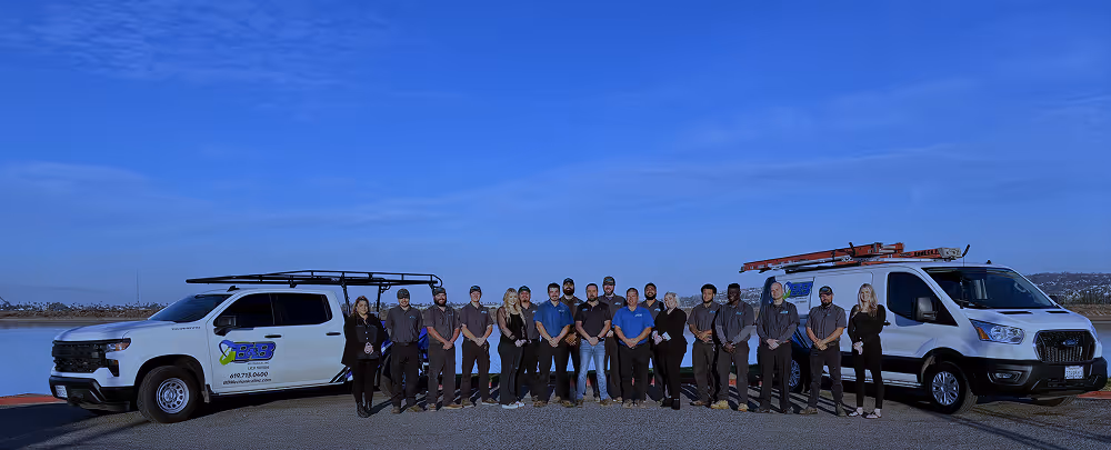 Team of professionals posing with work vehicles against blue sky backdrop