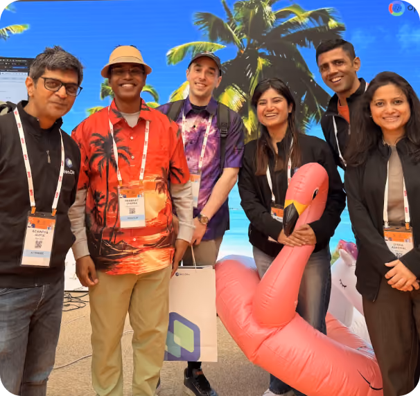 Reo.Dev team members posing with conference attendees in front of a tropical-themed event backdrop.