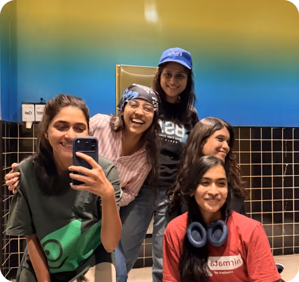 Five colleagues smiling together for a mirror selfie during a casual team outing.