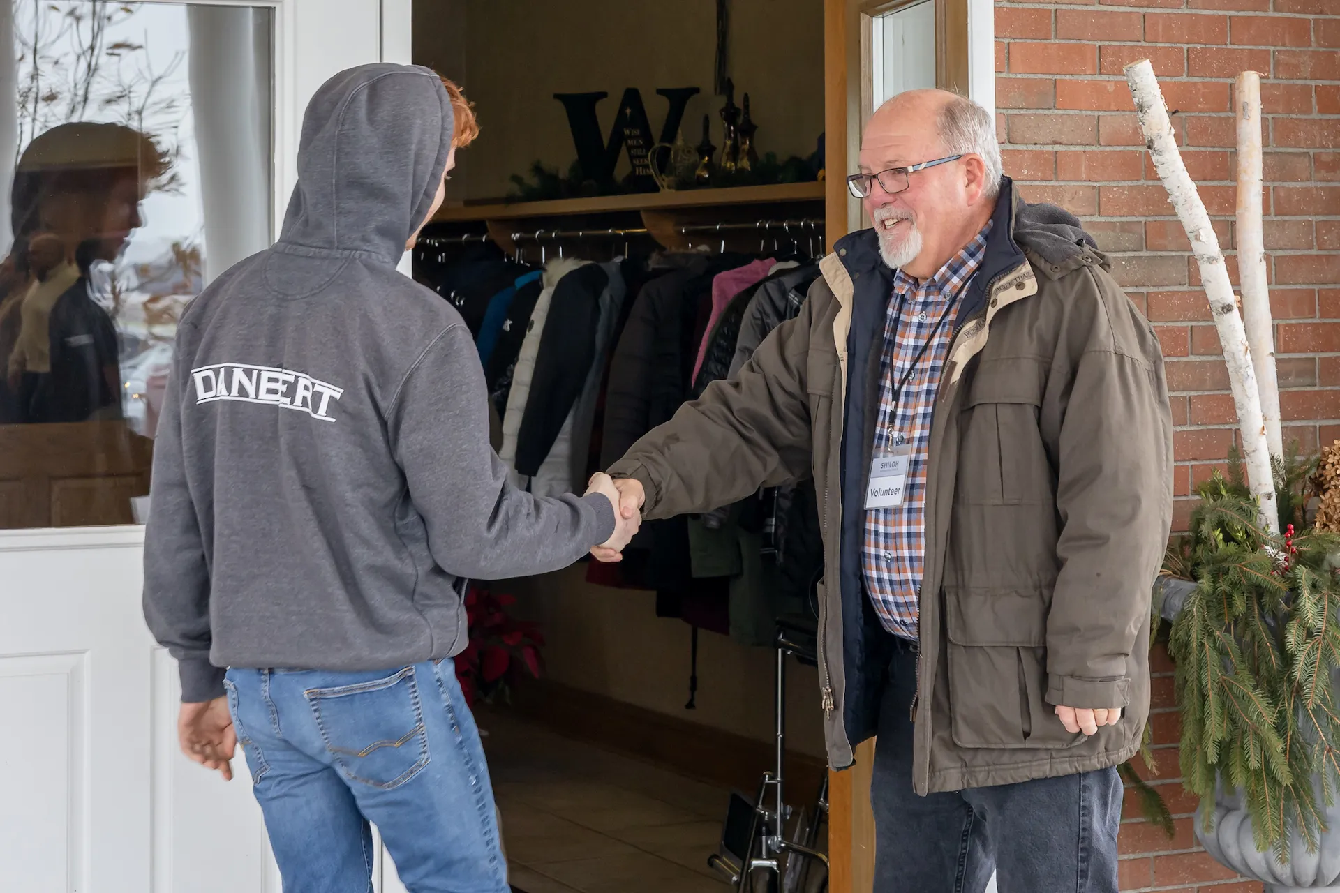 A young man shakes hands with an older man welcoming him into the service.