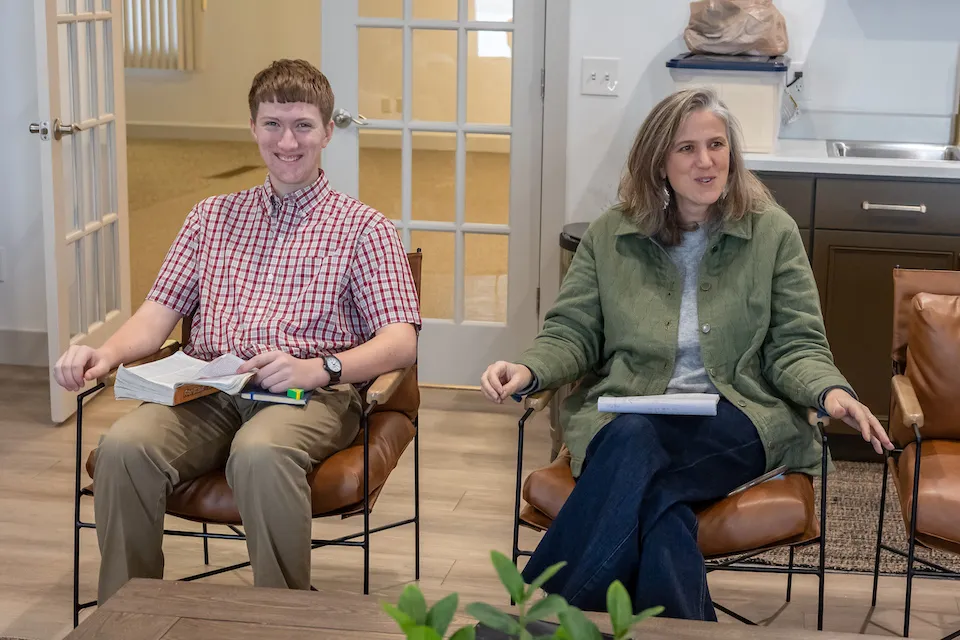 A young man and a woman sit in a modern room, leading discussion.