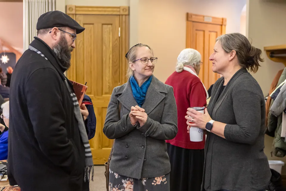 Three people chatting in the lobby at a Sunday gathering.