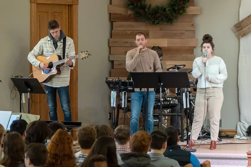 Three performers on stage leading in worship.