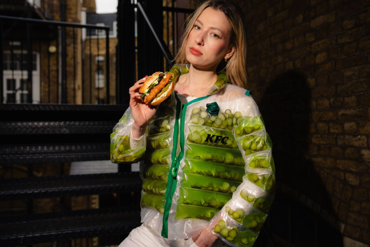 Model wearing the KFC pickle puffer jacket built by Nexform, photographed on a Shoreditch fire escape