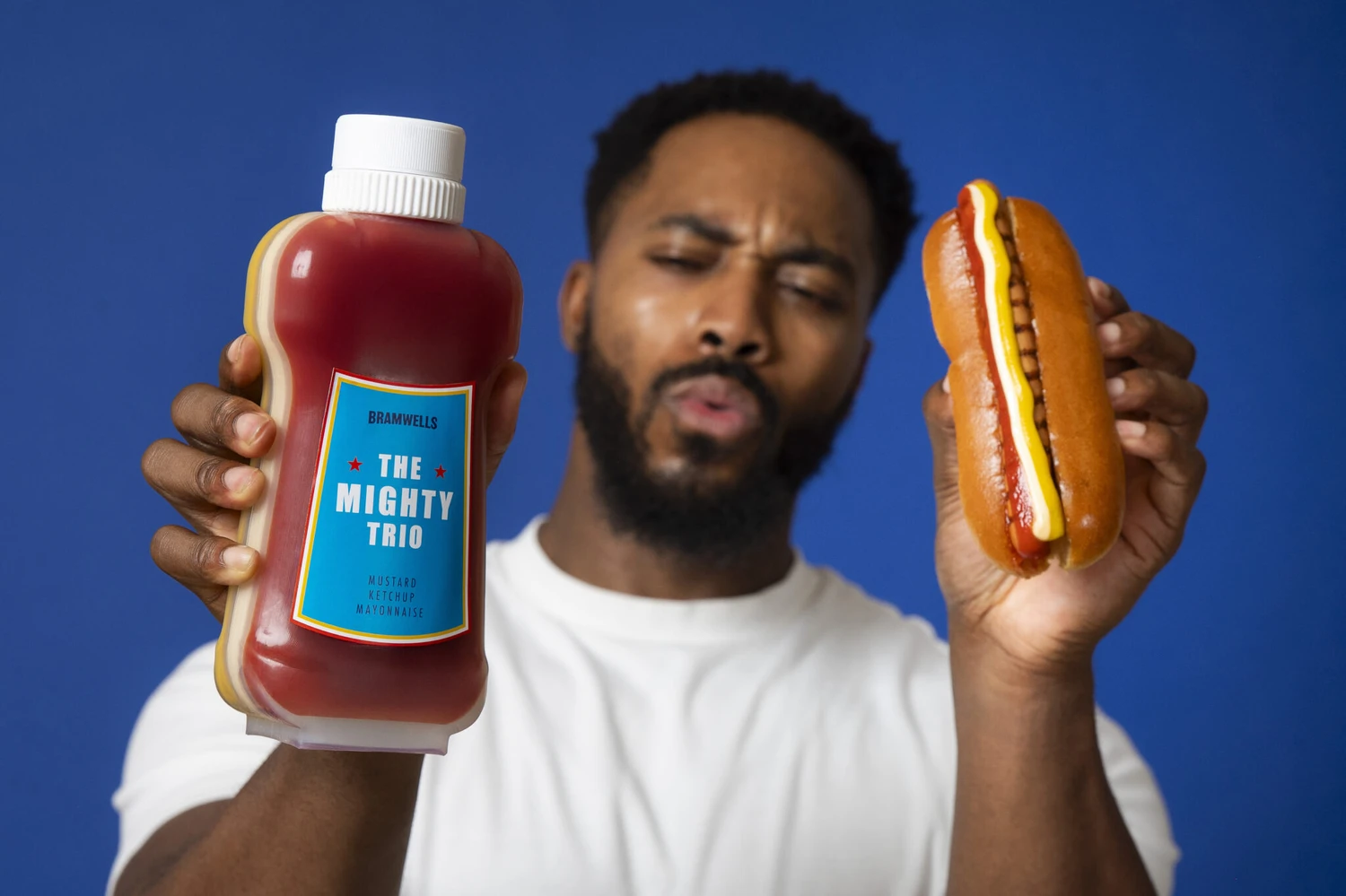 Bramwells triple-chamber bottle dispensing three sauces onto a hot dog