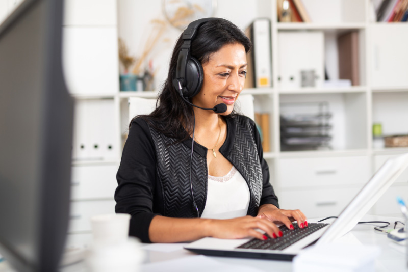 stock photo woman wearing headset typing on laptop