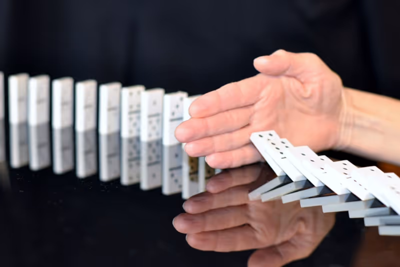 stock photo hand blocking dominoes falling