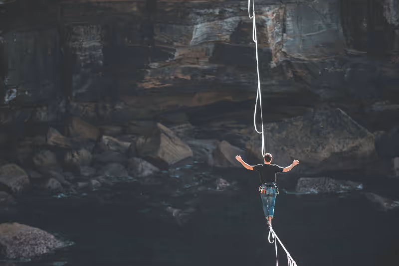 stock photo person walking tightrope over canyon