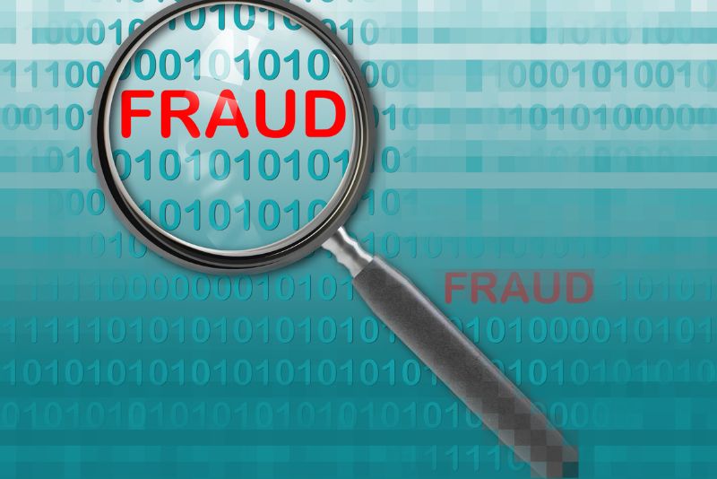 stock photo magnifying glass over word fraud in red