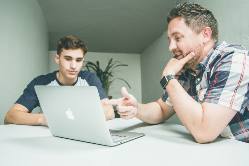 stock photo two men discussing over open laptop