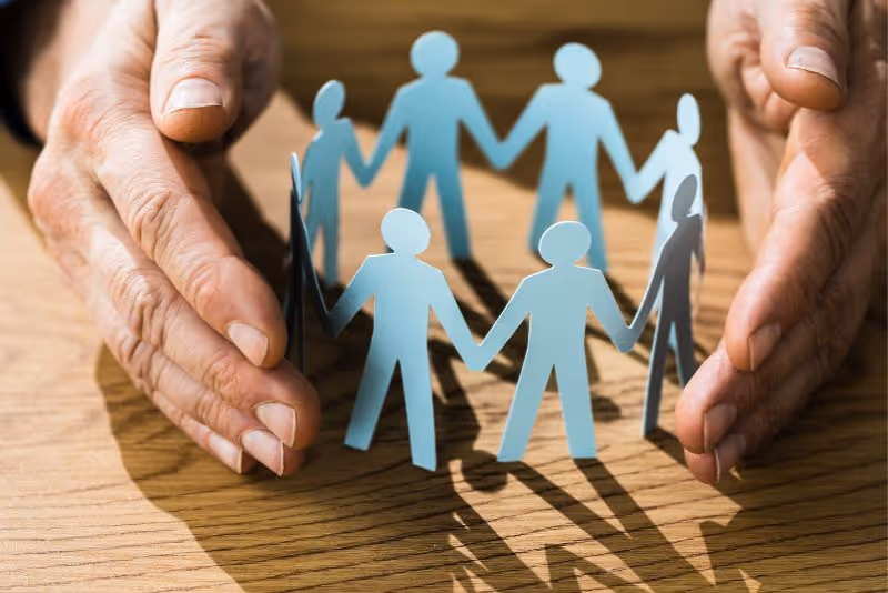 stock photo hands surrounding paper cutout figures