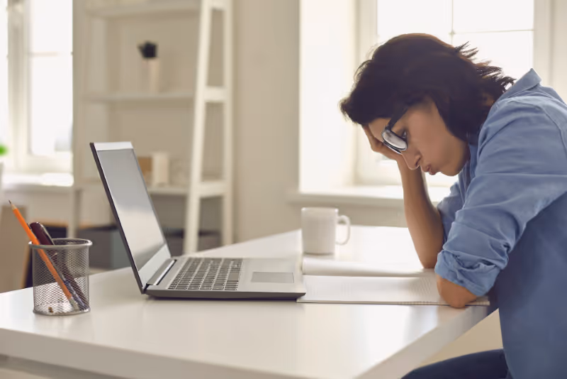 stock photo woman with head in hands at table with laptop
