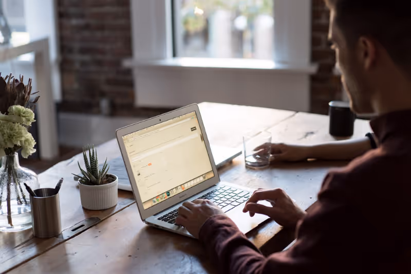stock photo man on laptop at table with another person