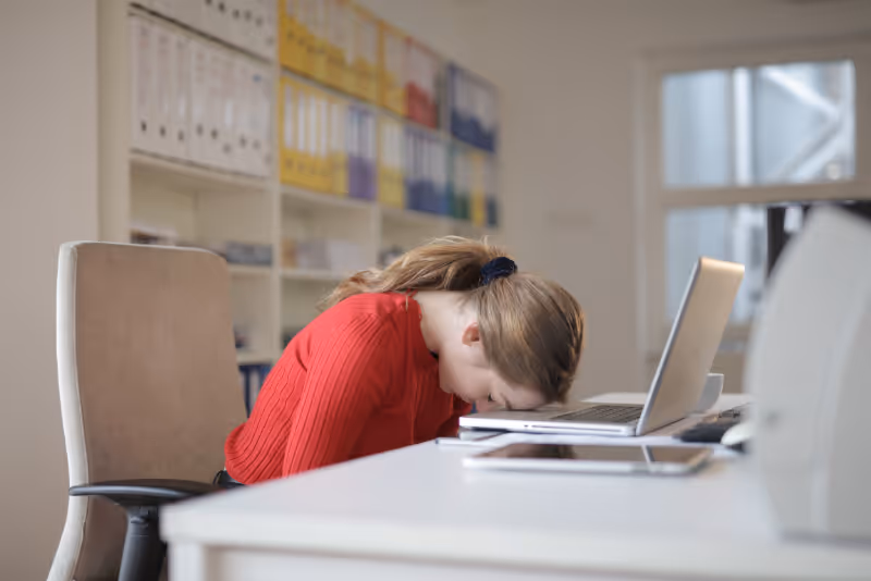 stock photo woman with head down on desk with laptop open