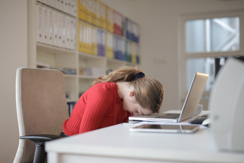 stock photo woman with head down on desk with laptop open