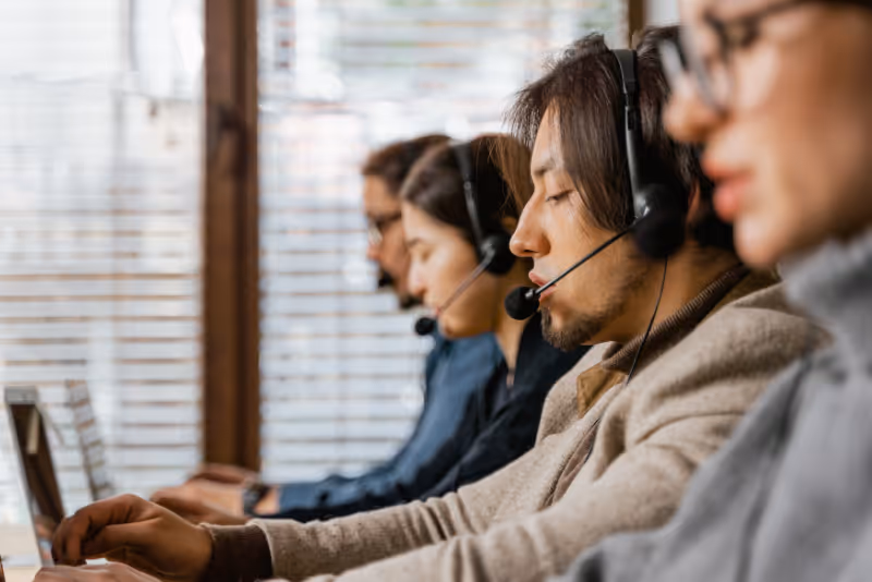 stock photo closeup on line of call centre workers with headsets
