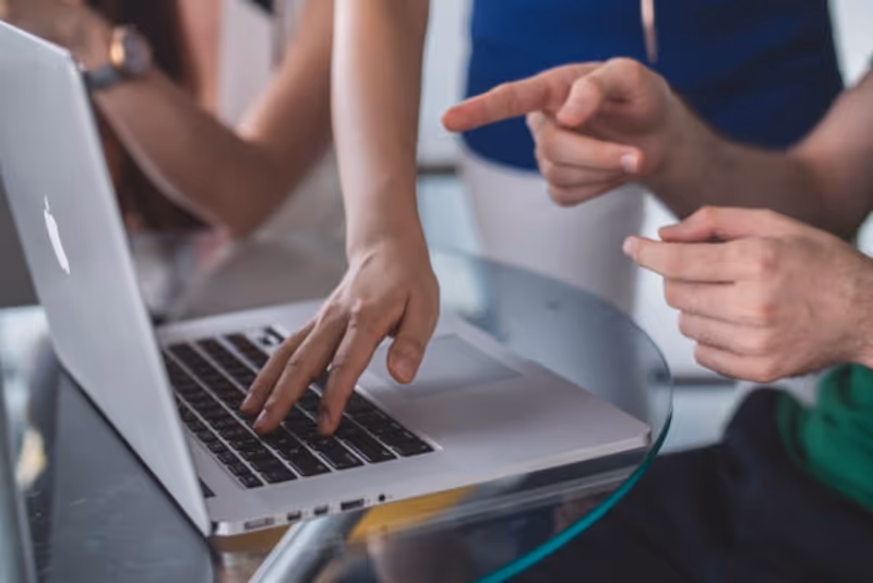 stock photo multiple people conversing around laptop