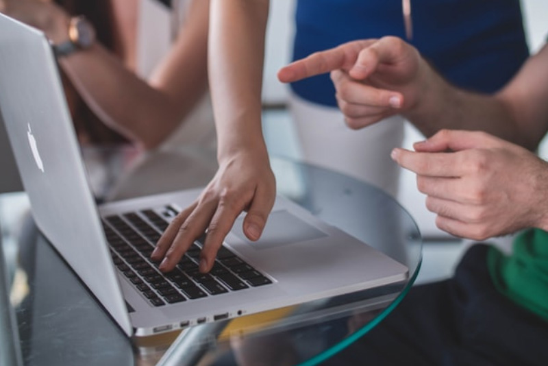 stock photo multiple people conversing around laptop