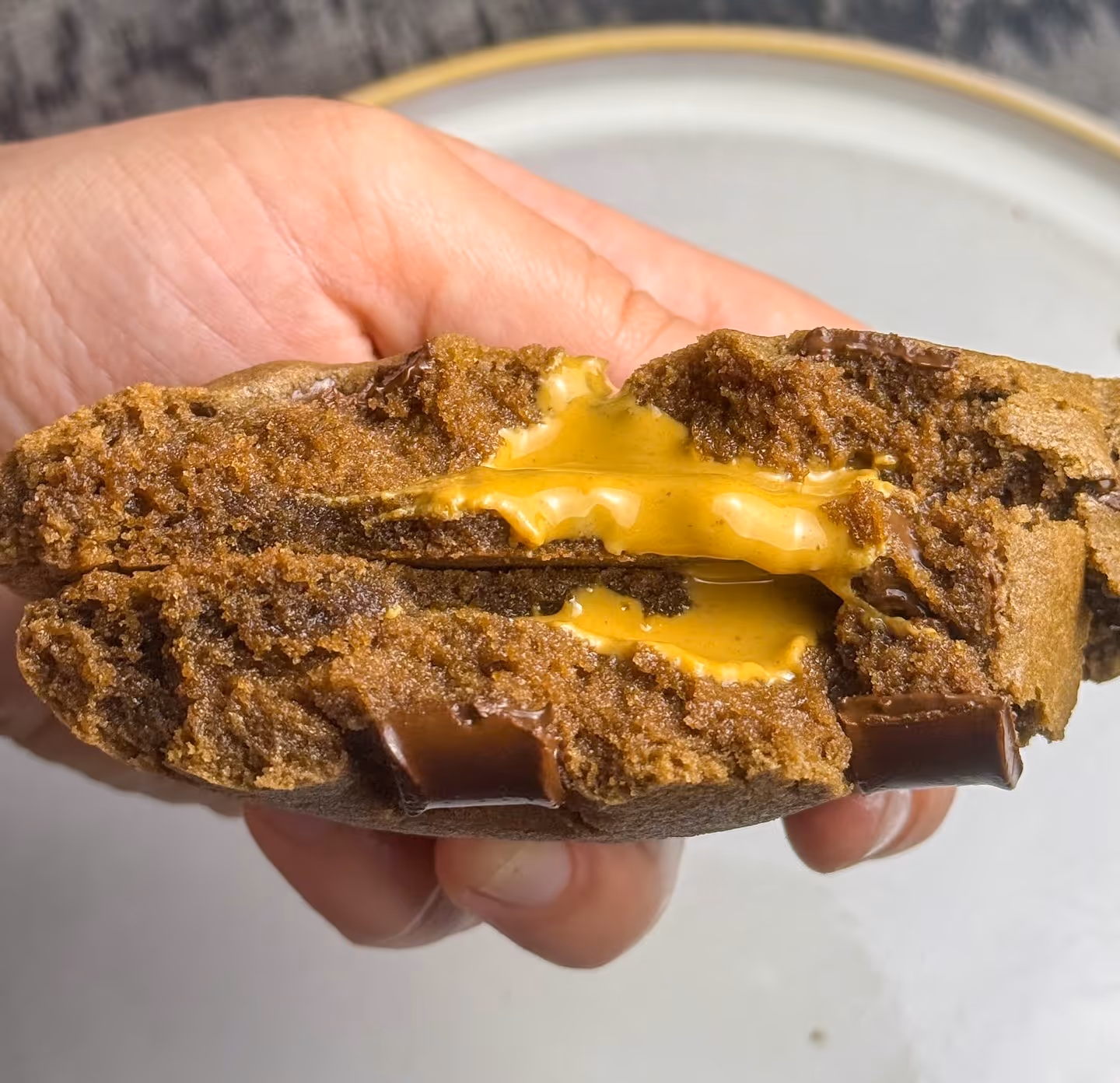 Chocolate Penut Butter Melt Cookie being held up to the camera over a plate.