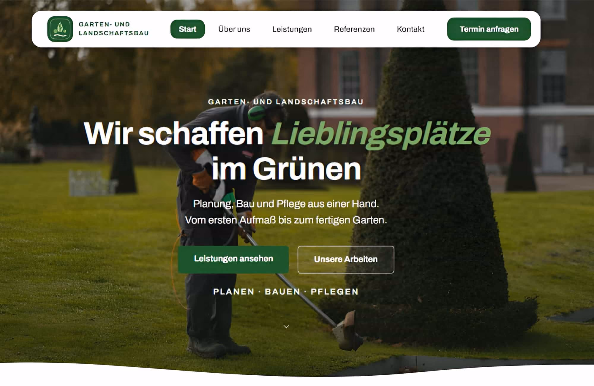 Gärtner mit Gehörschutz und Handschuhen trimmt Rasen an einer hoch geschnittenen Hecke in gepflegtem Park mit alten Gebäuden im Hintergrund.