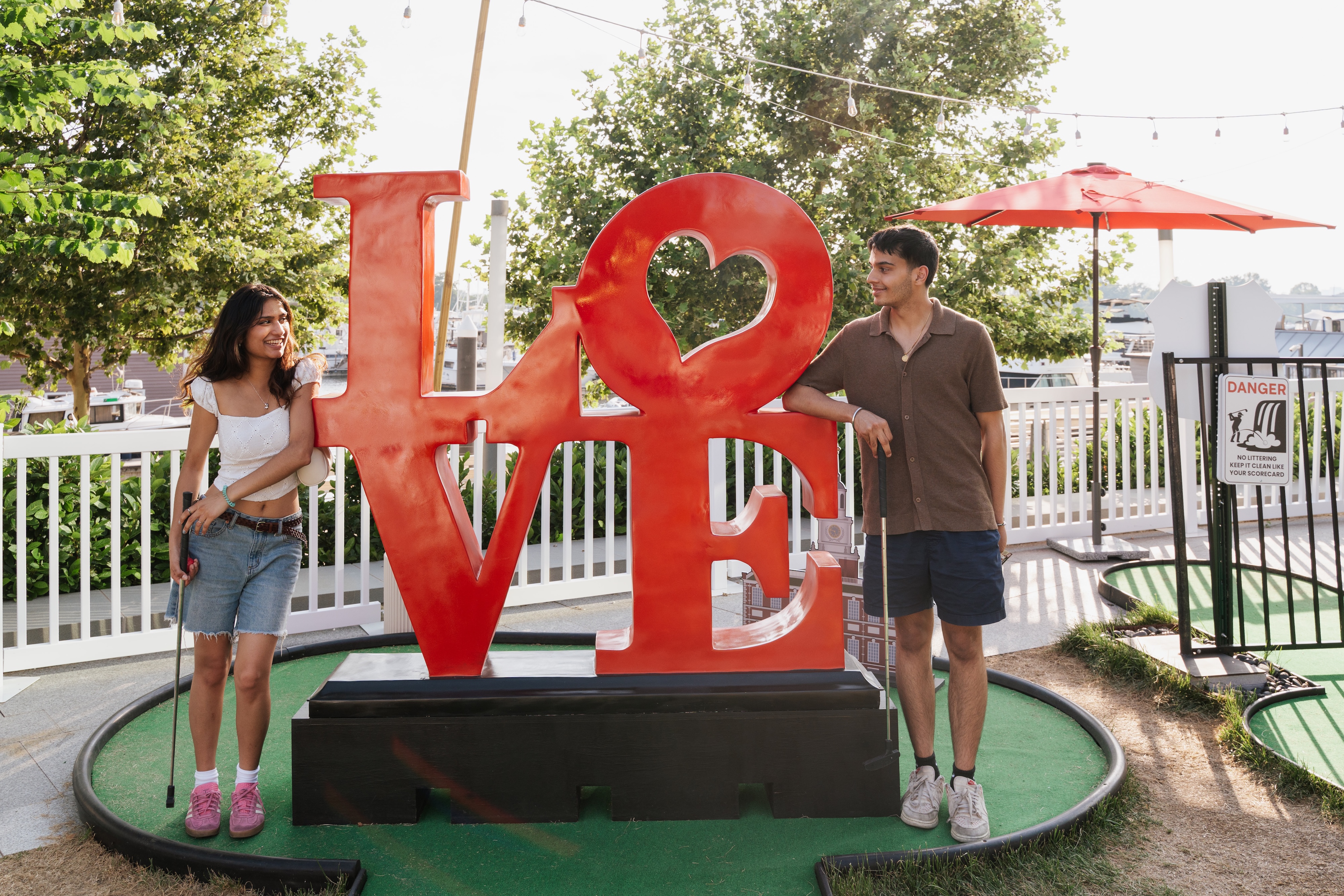 Couple looking at each other by a LOVE sign