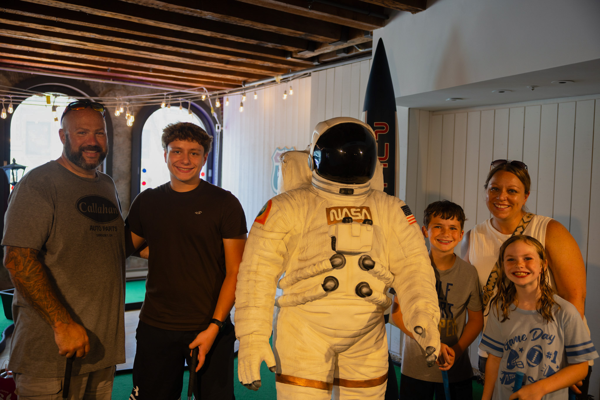 Family posing with astronaut statue at Putt Across America