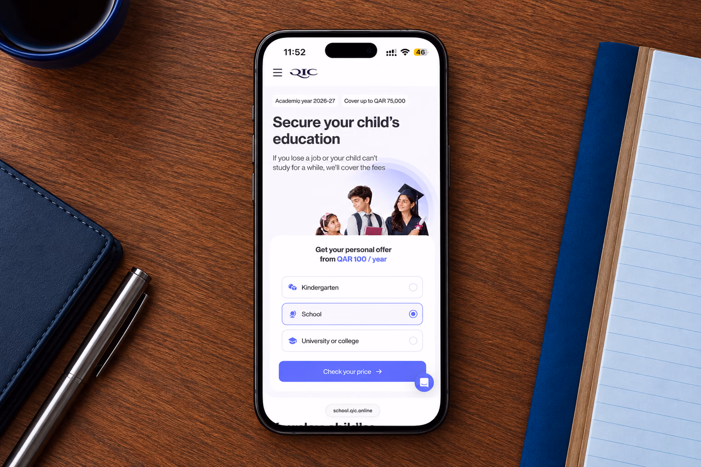 Smartphone on a wooden desk displaying a QIC webpage offering coverage for school fees up to QAR 75,000 for the academic year 2026-27, with options to select Kindergarten, School, or University/college and a button to check the price.