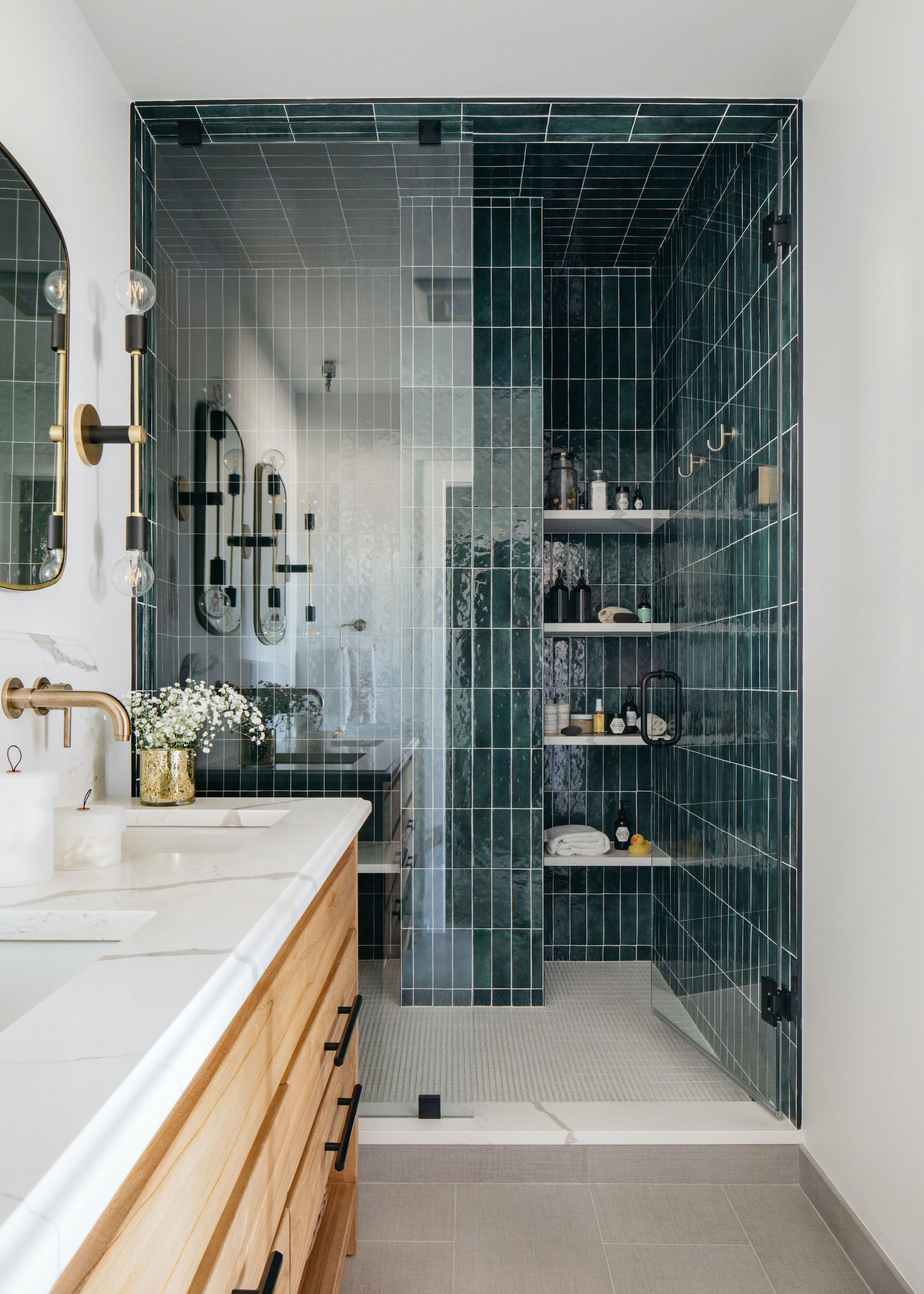a small bathroom with an open shower that has open shelving inside. On the shelves are essentials such as shampoos, body wash