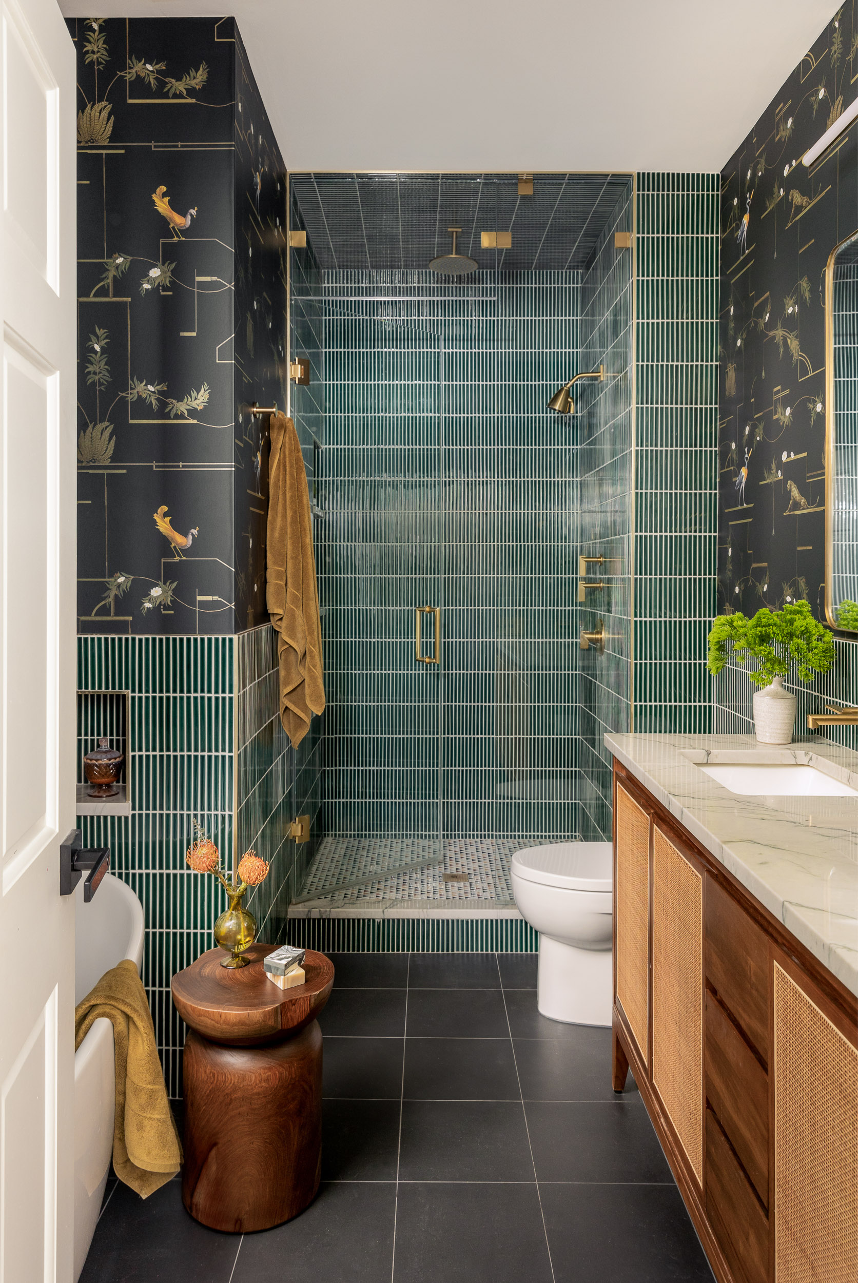 A bathroom covered in hunter green tile and gold/orange hardware and accents.