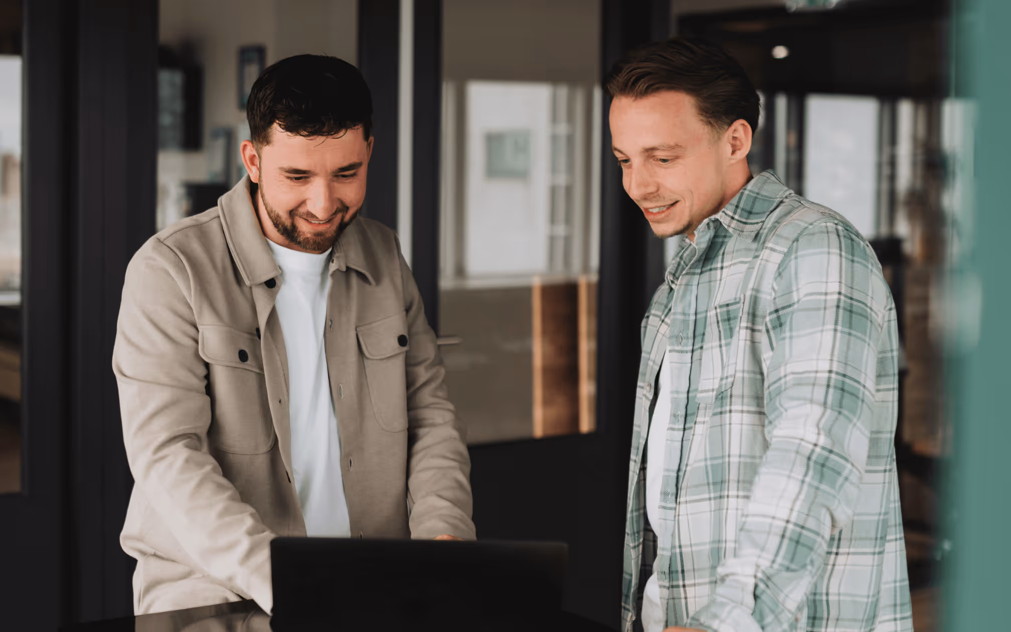 Collega’s in gesprek op kantoor bij een laptop.
