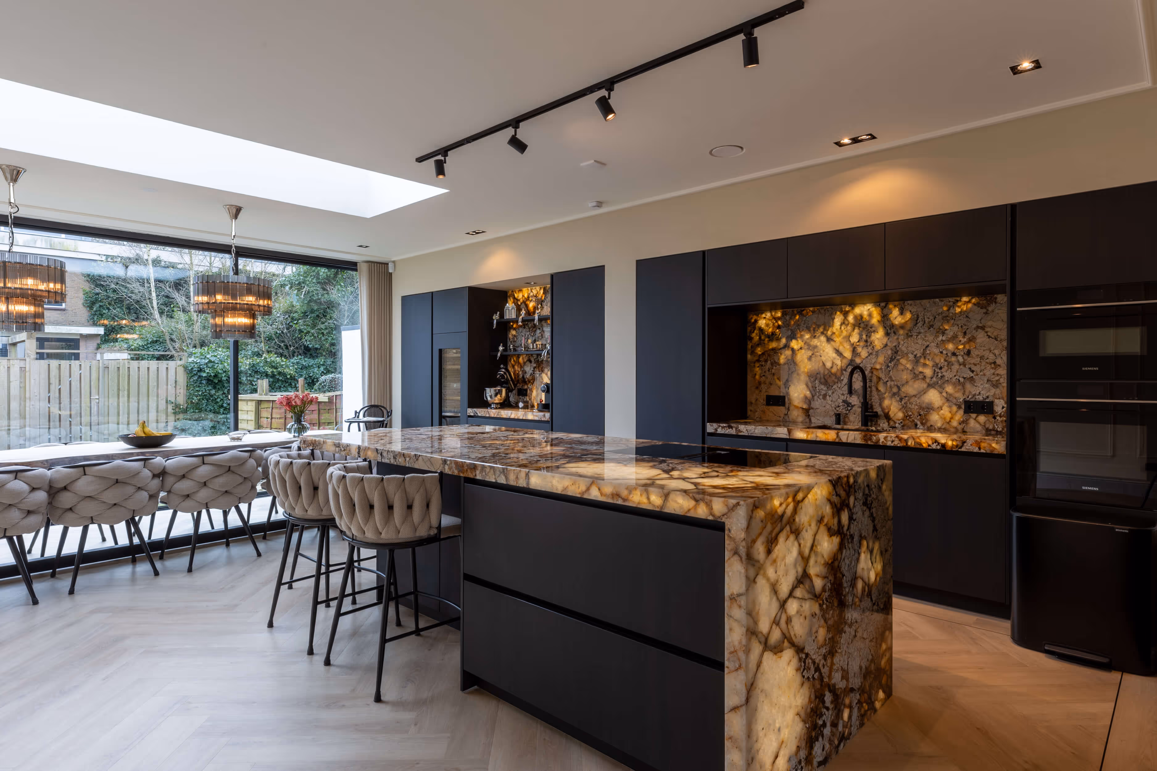 Moderne keuken met marmeren kookeiland en strakke zwarte kasten.