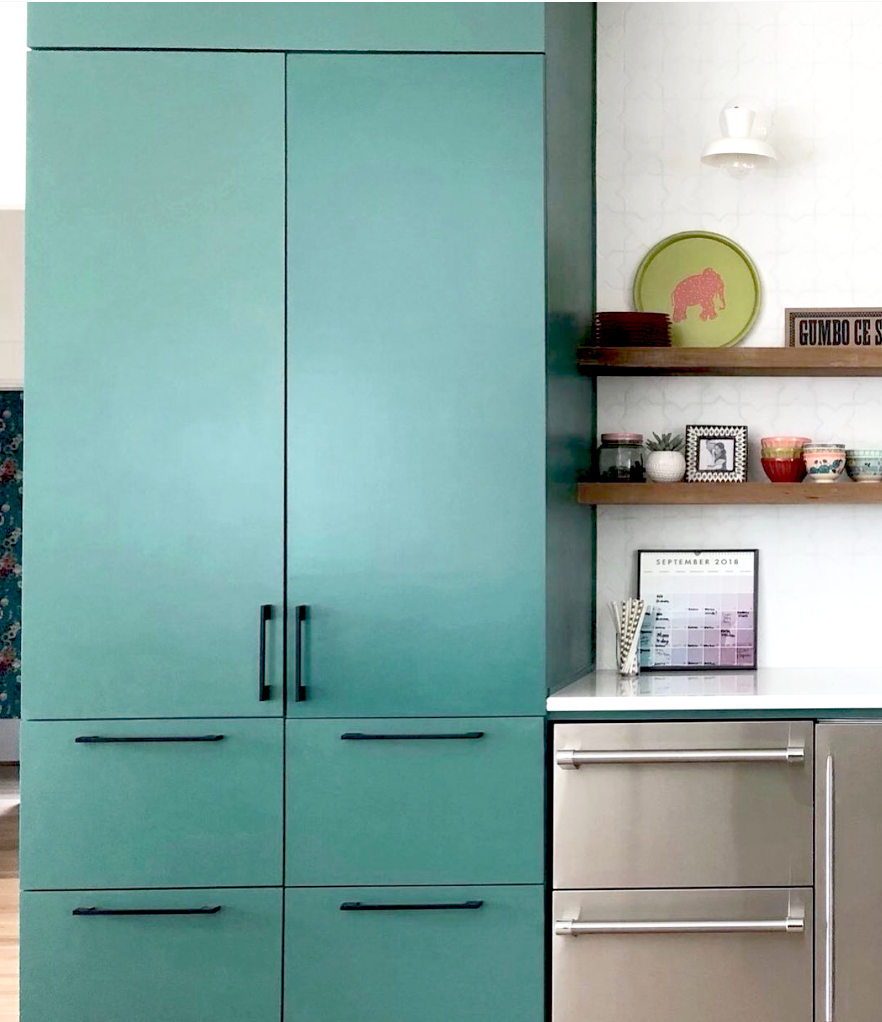 This gorgeous teal pantry cabinet stands out next to the well built shelving in this bright space.