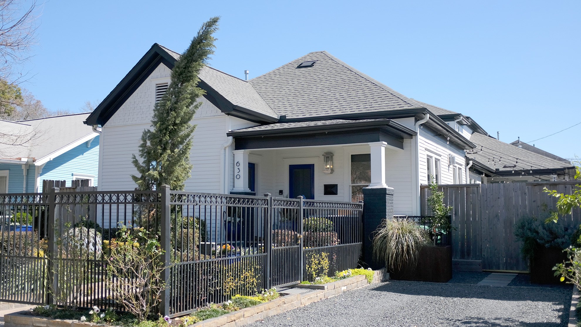 This stunning bungalow has a beautiful green tree in the fenced front yard.