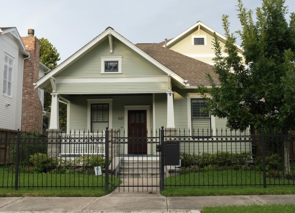This light green bungalow is absolutely gorgeous sitting behind a short black iron fence.