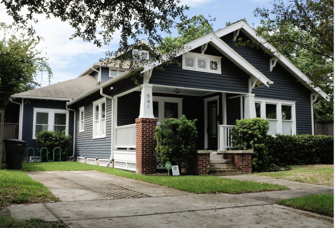A navy blue bungalow house looks idillic in it's Houston Heights location.
