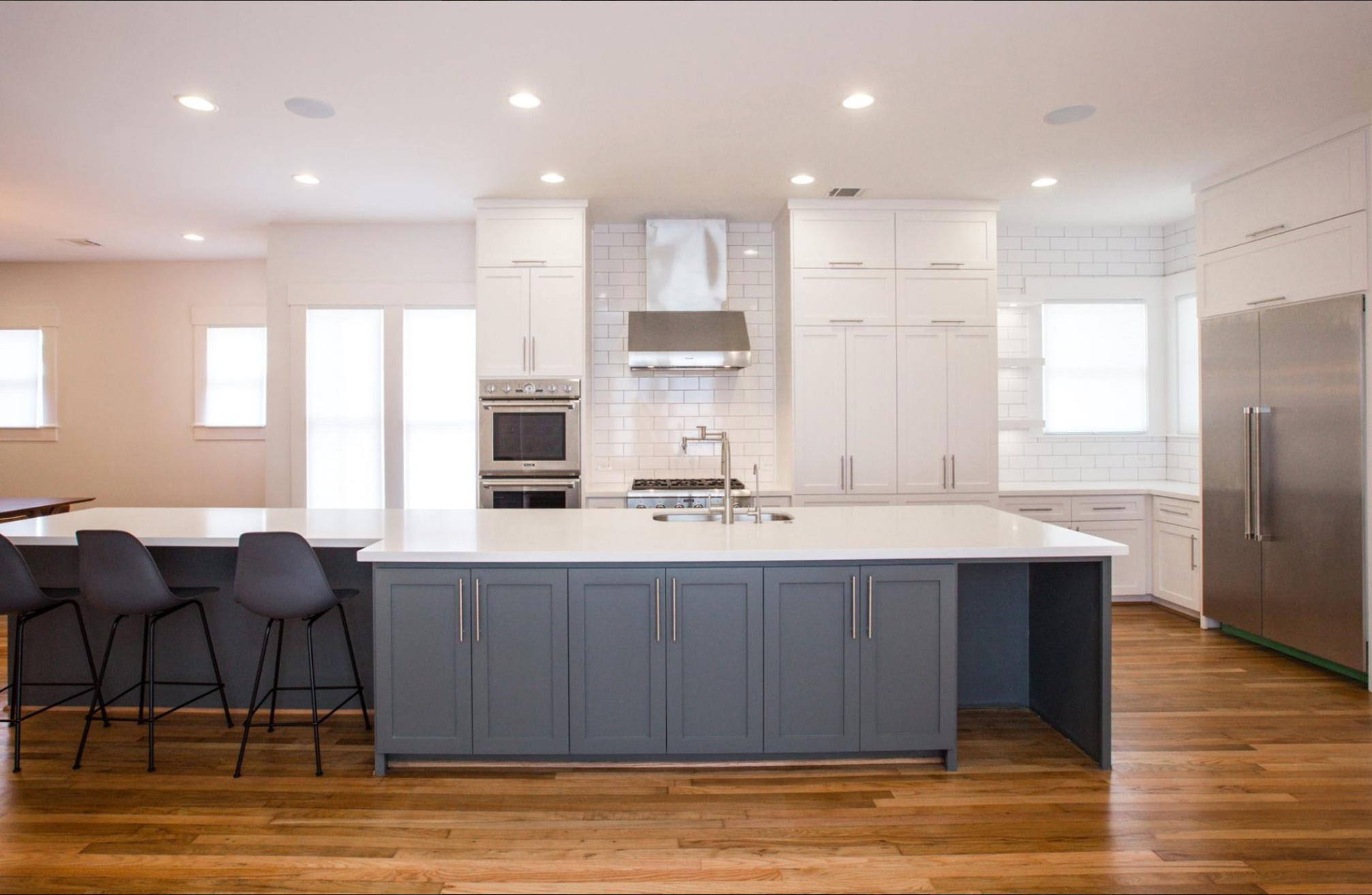 A revnovated kitchen is filled with light with wood floors and new appliances.