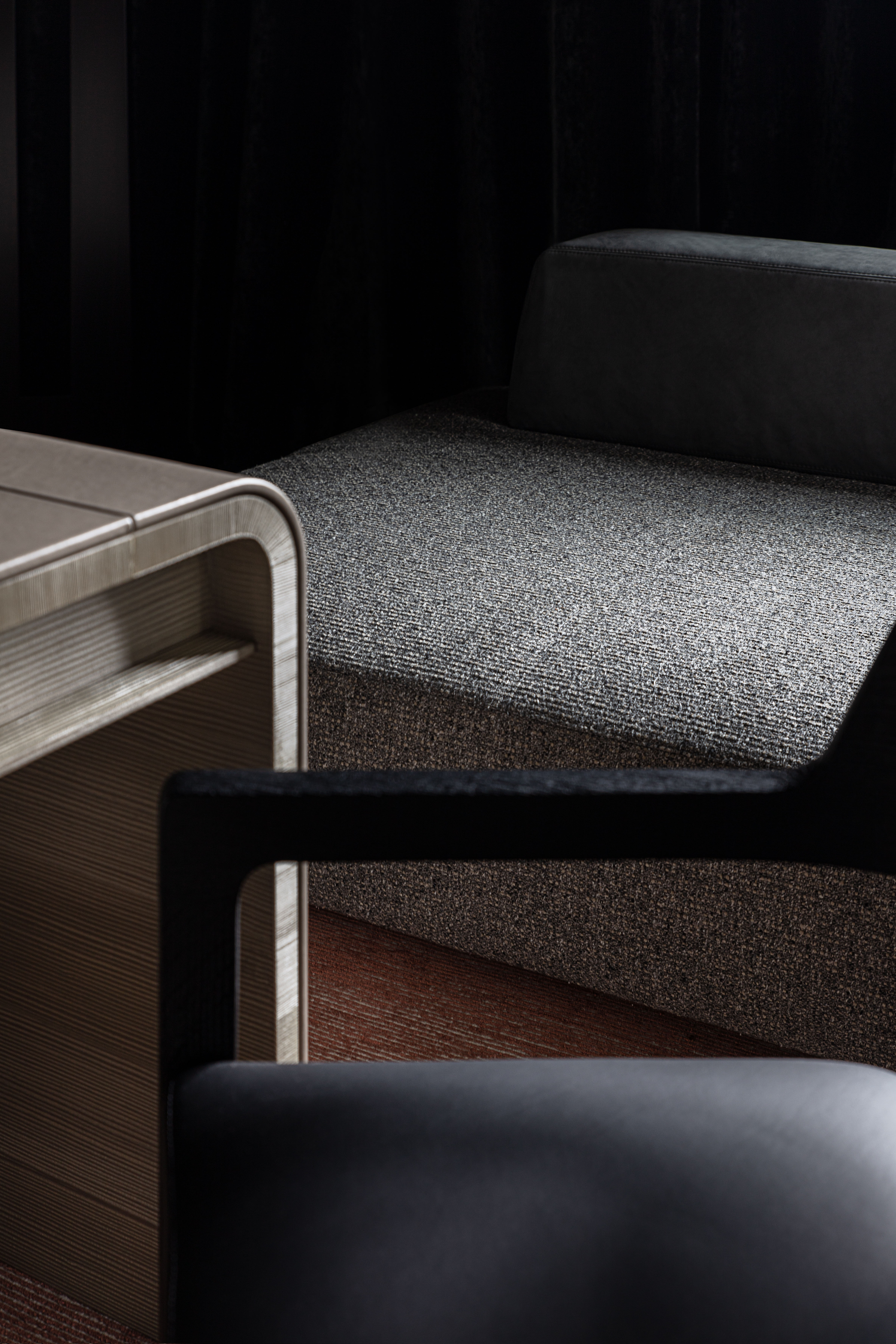 A study with black walls, a grey desk, and a golden torso.