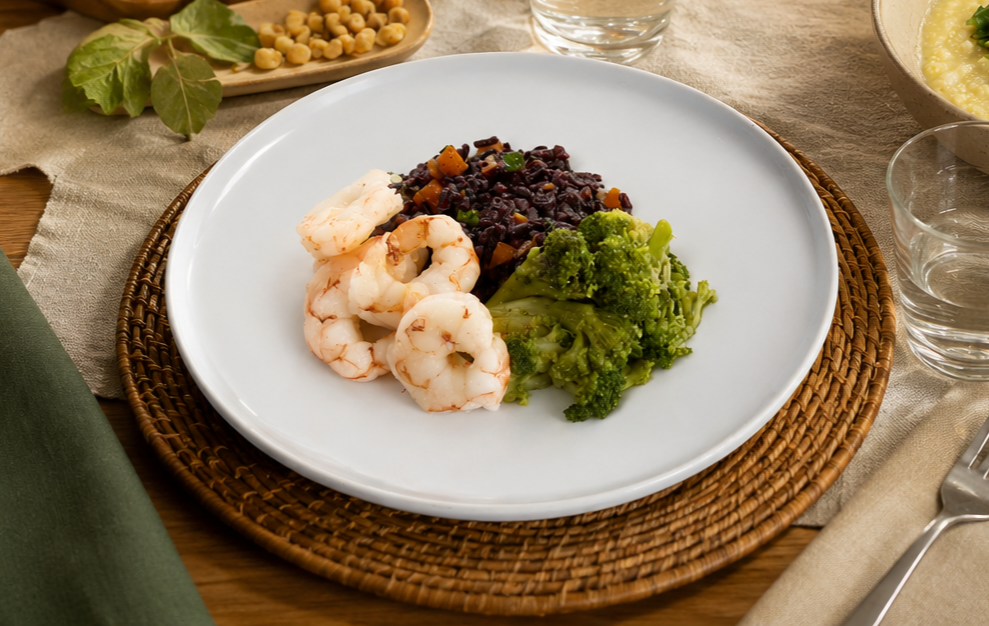 Ciotola di crema di polenta con bietole verdi al centro, accanto a foglie fresche e chicchi di mais secchi su superficie scura con un cucchiaio in acciaio.
