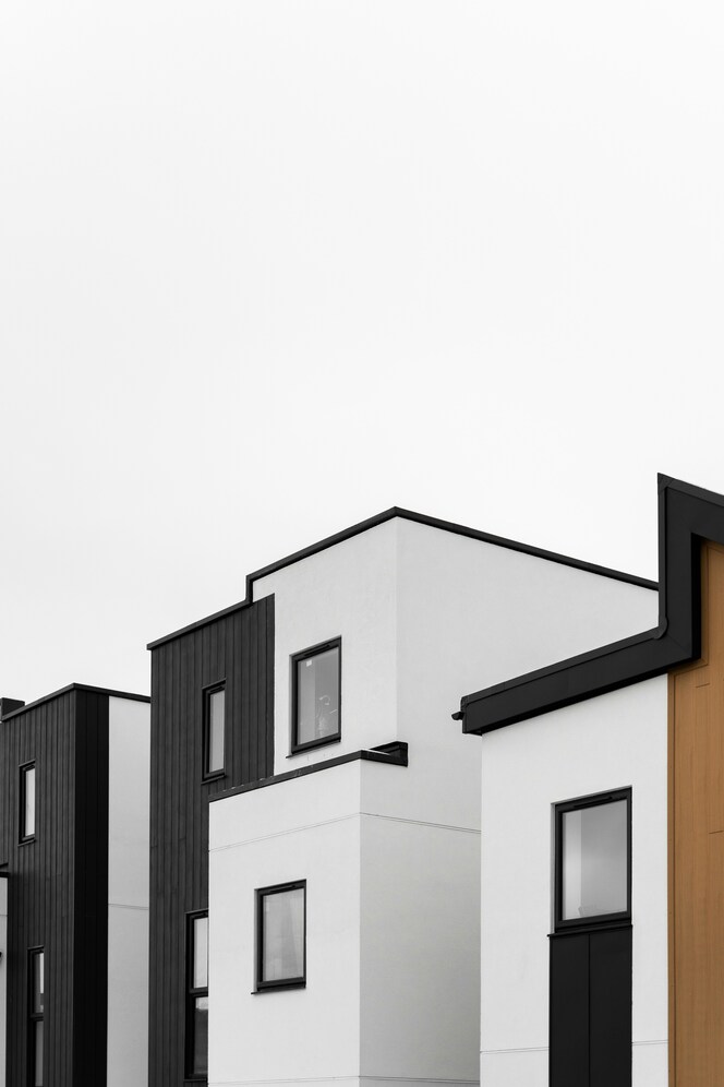 Modern white and black buildings with clean lines and rectangular windows under an overcast sky.