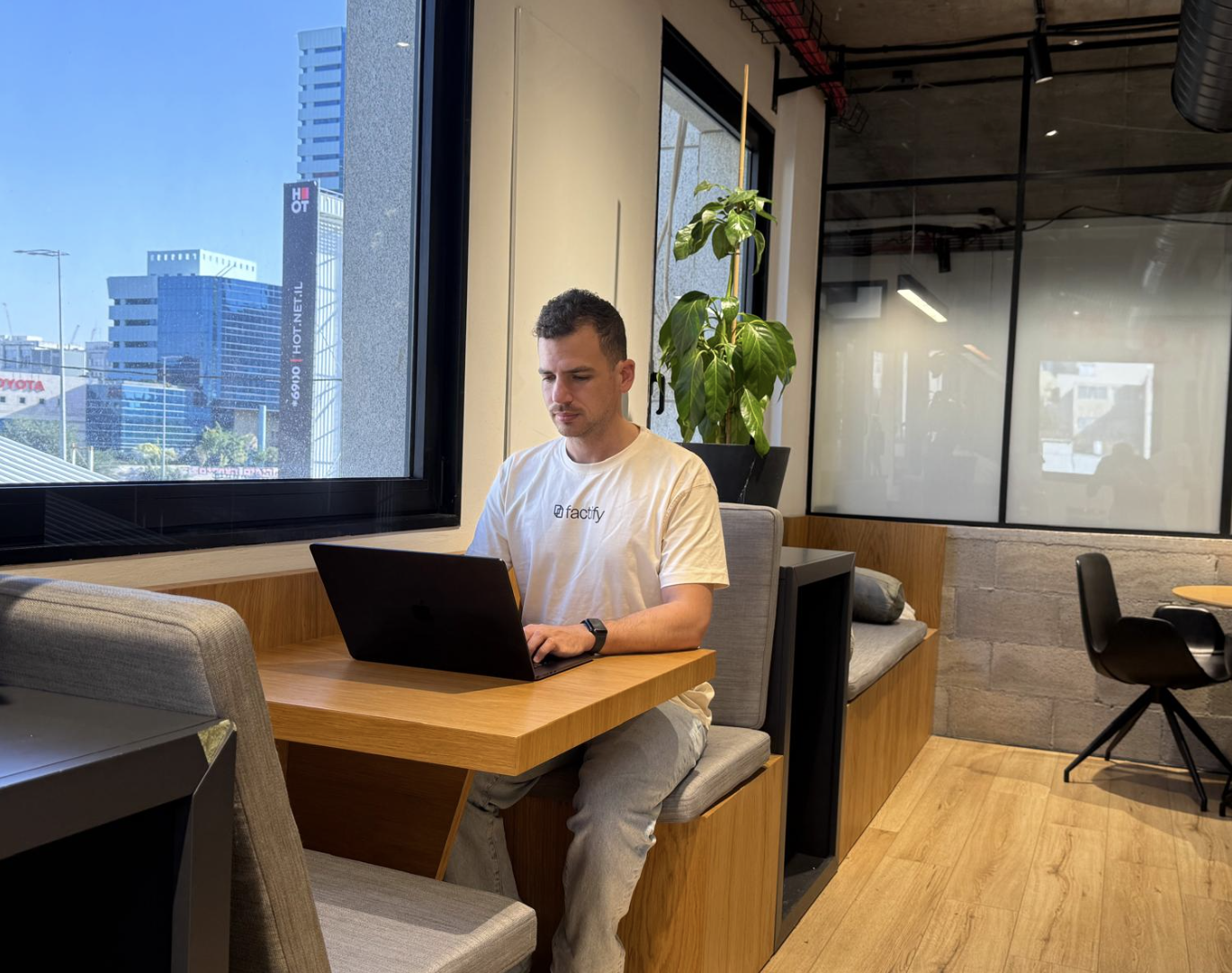 A teammate working at a laptop by the office window